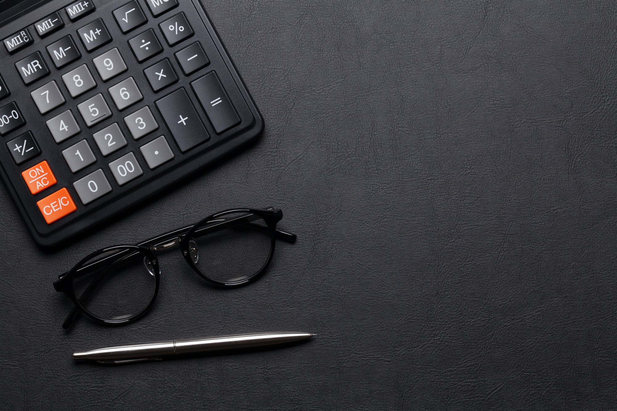 Office desk table with calculator, pen and glasses